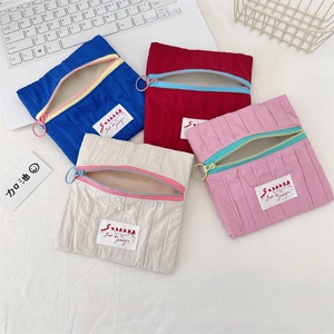 Flat lay of colorful pleated zipper pouches with metal rings on a desk setup