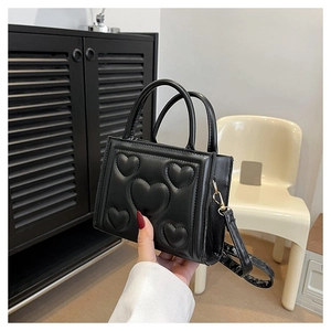Détail d'un sac en cuir PU noir avec motifs de cœurs gaufrés et finitions dorées