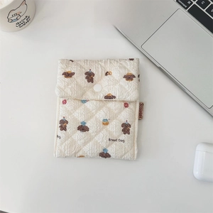 Close-up of quilted cream pouch with cute bread dog pattern and soft textured finish