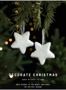 Sparkling white star Christmas ornaments hanging on a pine branch with festive bokeh
