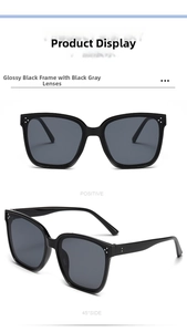 Detail view of large black frame sunglasses with silver rivet accents and grey lenses