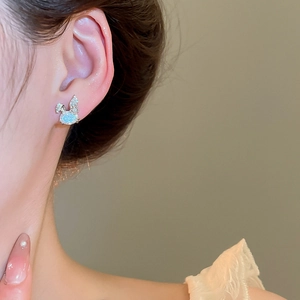 Close-up of minimalist silver rabbit stud earring with blue opal stone on female model ear