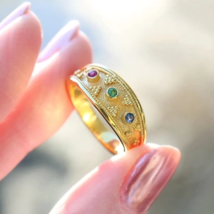 Macro shot of vintage gold ring with filigree detail and three colorful gemstones