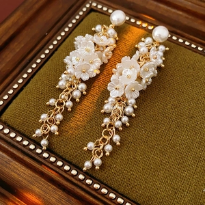 Close-up of golden tassel earrings with resin flowers and pearls in a vintage jewelry box