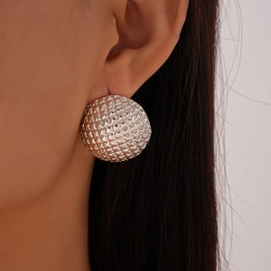 Macro shot of silver spherical stud earrings with textured geometric diamond-cut patterns