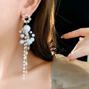 Detail of elegant gold tassel earrings with pearls and rhinestones on a model