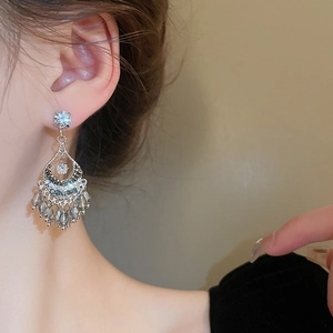 Ethnic style crystal fan earrings with teardrop tassels shown on a model side profile