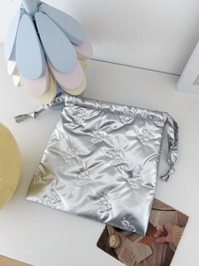Detail of silver metallic drawstring bag with bow embroidery and puffy padded texture