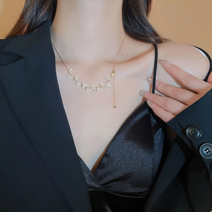 Dettaglio di una collana a fiori placcata in oro con piccoli diamanti su modella elegante