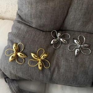 Detailed macro shot of gold and silver textured flower earrings on grey linen fabric