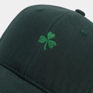 Close-up of green clover embroidery on dark green cotton twill baseball cap with stitching