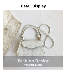 Detailed view of white embossed leather handbag with metal corner protectors and knotted handle