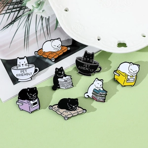 Close-up of assorted enamel cat pins featuring cute kittens on books and in coffee cups