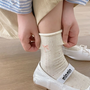 Detail view of cream mid-calf socks featuring pink bow embroidery and ribbed cotton texture