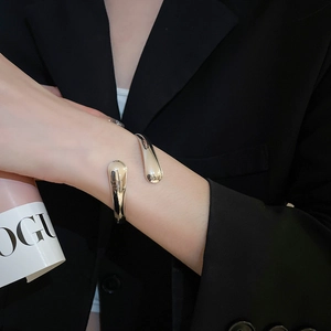 Close-up of a silver polished water drop cuff bracelet worn over a black blazer sleeve