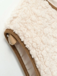 Detailed macro view of white sherpa fleece fabric with a wooden toggle button closure