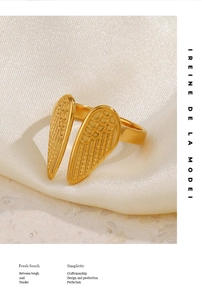 Detailed view of 18K gold plated wing ring on white silk, showing intricate feather texture