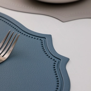 Blue leather place mat with vintage texture and decorative stitching on a white table