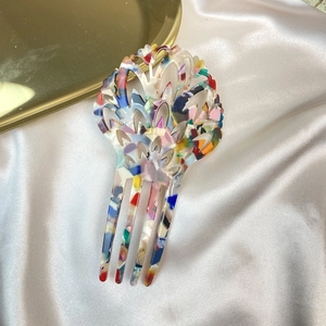 Detail of tortoise shell acetate hair fork with hollow design on white silk background