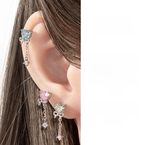 Detail of heart zircon bow earring with a long chain drop on a model's ear