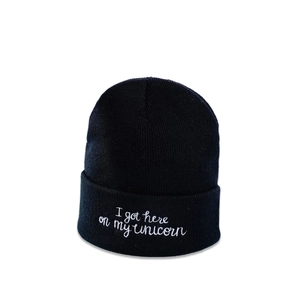 Detail of black knitted beanie with white I got here on my unicorn embroidery