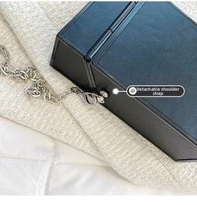 Detail showing the detachable silver chain strap and crosshatch texture of the square bag