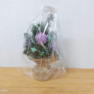 Mini green Christmas tree with purple glitter balls and a rustic burlap base detail