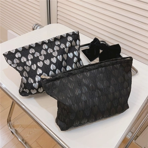 Detail of black heart-patterned cosmetic bags with silver jacquard and metal zipper