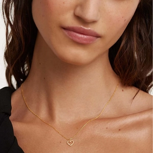 Close-up of elegant gold hollow heart pendant necklace worn on a woman's neck