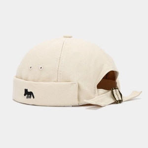 Detailed close-up of beige canvas miki hat with black animal embroidery and metal buckle