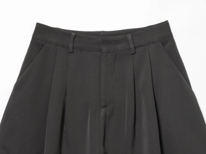 Détail de la taille d'une jupe grise foncée avec passants et plis sophistiqués