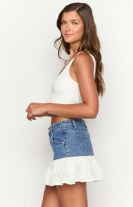 Detail of high-waisted denim mini skirt with delicate white lace patchwork and ruffled hem