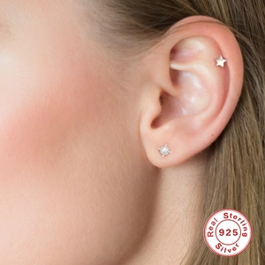 Detail of 925 sterling silver star stud and pearl earring on model earlobe