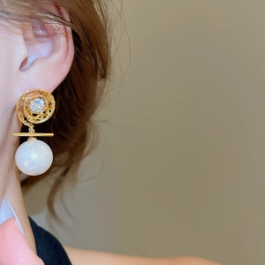 Close-up of 14K gold plated swirl earrings with large white pearl and zircon accents
