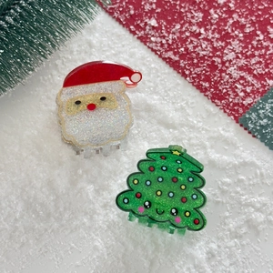 Detail of acrylic Santa Claus and sparkling Christmas tree hair claws on snow background