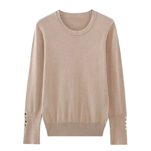 Detailed view of knitted long sleeve cuffs with decorative gold metal buttons