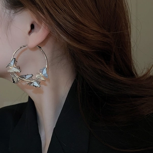 Side view of model wearing large butterfly hoop earrings with gold and silver metallic finish