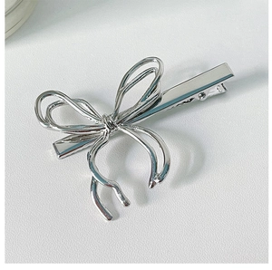 Detailed close-up of a silver liquid metal bow hair clip with irregular texture