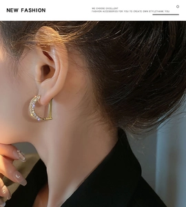 Close-up of D-shaped gold earrings with micro-pave white zircons on a female model