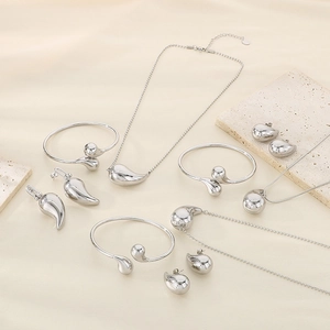Polished silver water-drop jewelry set with necklaces and earrings on silk background