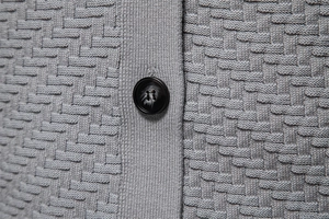 Macro shot of textured black button on a grey waffle knit men's v-neck cardigan