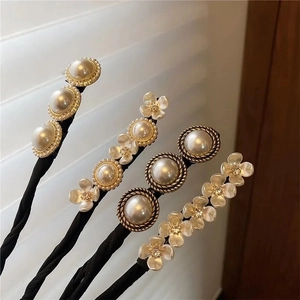 Detalle de cuatro elegantes horquillas para el pelo con perlas y flores en espiral negra