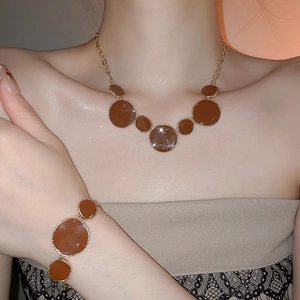 Gros plan détaillé sur un ensemble collier et bracelet doré avec des pendentifs marron
