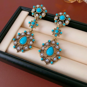 Macro detail of vintage gold drop earrings with turquoise stones and pearls in a jewelry box