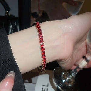Macro view of 18k gold tennis bracelet with square-cut red rubies and diamond accents
