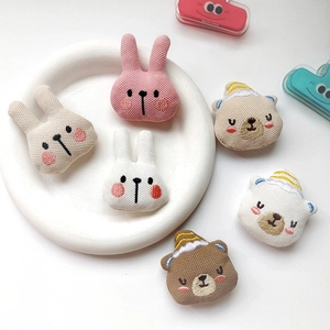 Close-up of six knitted animal heads including rabbits and bears in a white ceramic dish