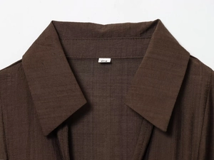 Détail du col d'une robe marron foncé avec texture verticale et étiquette de taille M