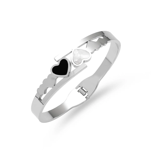 Detail of silver heart bangle showing black and white heart charms with hollow cutouts