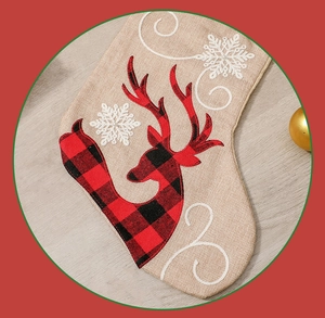 Detail of linen Christmas stocking featuring a red plaid reindeer and white snowflake embroidery