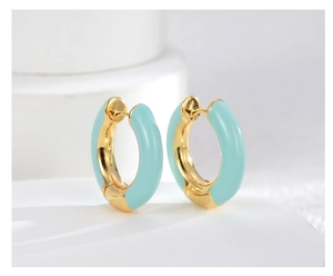 Detail of mint green enamel hoop earrings with polished gold-plated finish on a white surface